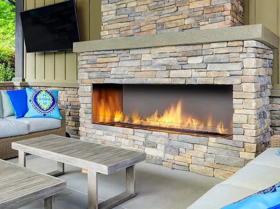 A Regency outdoor gas fireplace burning on a covered patio