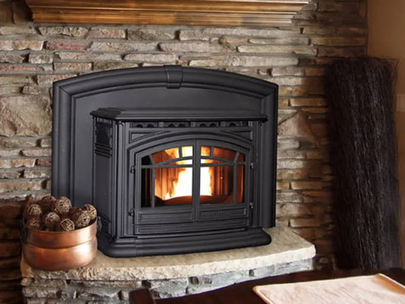 An Enviro M55 cast-iron pellet insert burning in a stone fireplace