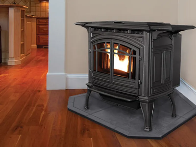 An Enviro M55 cast-iron pellet stove burning on a hearth pad