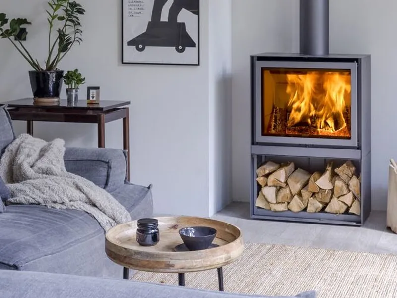 A Stûv wood stove with a log store burning in a living room