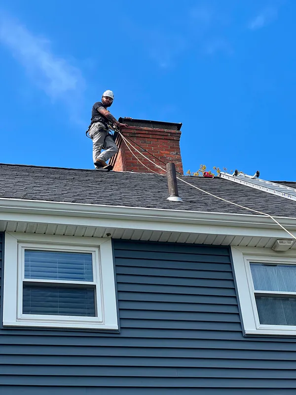 Technician on a roof fitting a chimney cap