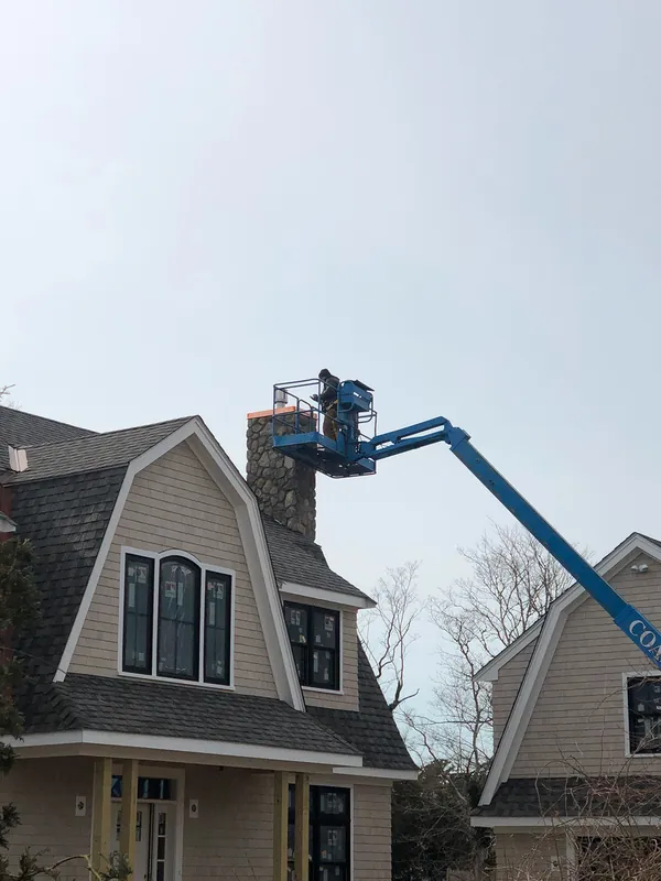 Chimney work from a boom lift on a gambrel-roofed house