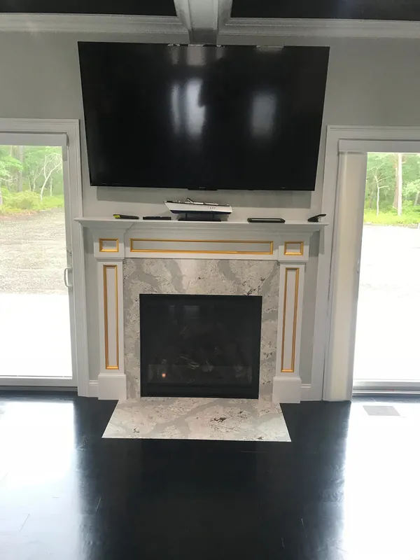 A linear fireplace in a marble surround below a television