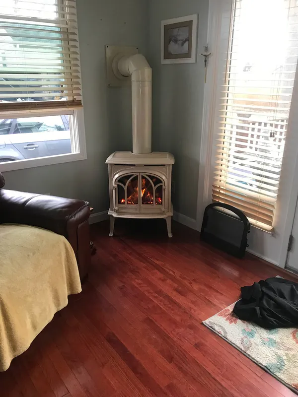 A cast-iron gas stove in a sunroom corner