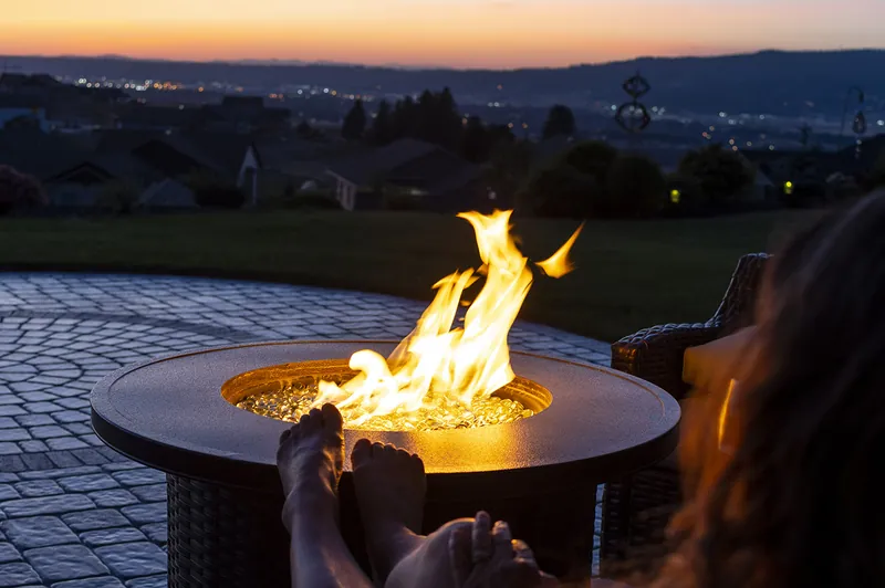 A round gas fire bowl on a patio at sunset