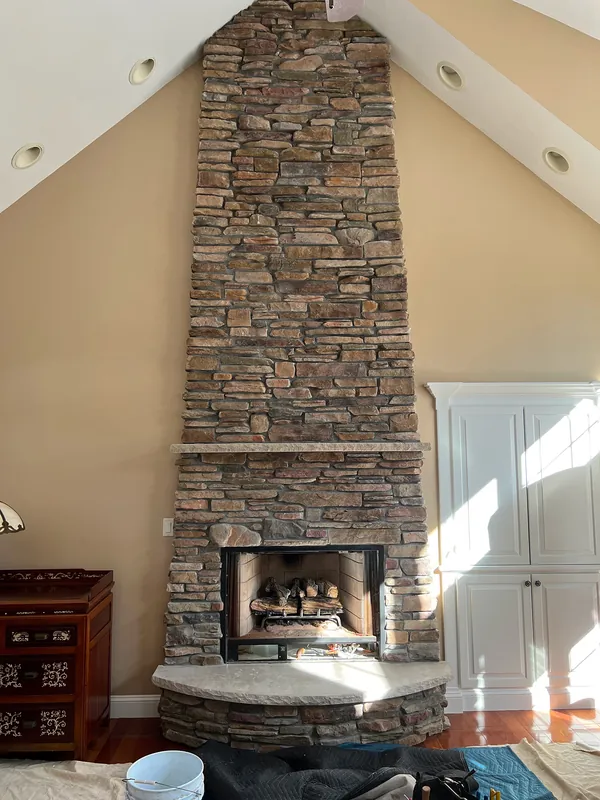 A floor-to-ceiling stone fireplace in a cathedral-ceiling room